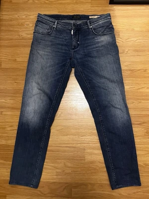 Antony Morato Jeans - Snygga mörkblå jeans från Antony Morato med slim passform och klassisk femficksmodell. Jeansen har en lätt tvättad look med subtila slitningar och är gjorda i ett mjukt denimtyg. Perfekta för en avslappnad och trendig stil.