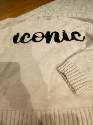 Beige stickad tröja med text - Beige stickad ”iconic” tröja!! En jätte fin begie tröja från Lindex i storlek 146/152 (xxs) som har texten iconic på sig🙌🏼💞 tröjan har bara testats på och är då aldrig använd! Precis som ny!! Ge gärna prisförslag🌟