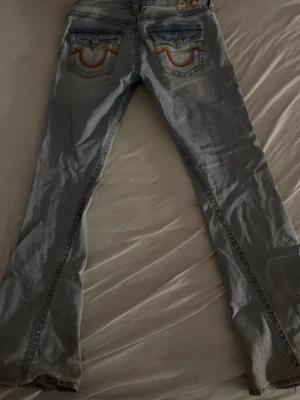 True Religion Joey Low Rise Flare Jeans - Säljer ett par ljusblå True Religion Joey jeans med low rise och flare passform. Har andvänt dom typ tre gånger så i bra skick men de är lite missfärgning pågrund av att jag har gått på dom sen ett litet hål vid fickan men syns knäppt när man har på dem💞💞