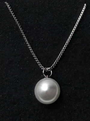 Silverhalsband med stor pärla I 316 rostfritt stål  - Snyggt halsband från Pilgrim med en stor, rund vit pärla som hänge. Kedjan är i silverfärg och har en klassisk, stilren design som passar till många olika looks. Perfekt accessoar för dig som gillar en elegant och enkel stil.           Detaljer: Material: 316 Stainless Steel (Rostfritt stål) Kedjetyp: Venetiansk kedja (Box chain) Pärla: 14 mm Kedjans längd: 50 cm Skick: Helt nytt / Oanvänt
