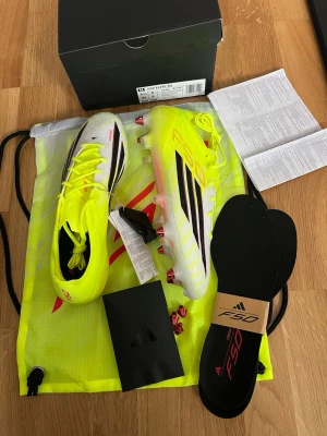 Adidas f50 elite sg  - Adidas f50 elite sg ”born for goals” i färgen Team Solar Yellow 2 / Core Black / Lucid Red. Nya kollektionen, storlek 42. Helt nya, inte ens provade. Tags kvar, kommer i originalkartong med tillhörande skopåse och extra sulor samt liten påse med extra dobbar + verktyg. Nypris 3099:- 