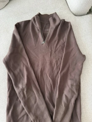 Massimo dutti halfzip tjockare variant - Snygg brun stickad tröja från Massimo Dutti med halv dragkedja och hög krage. Tröjan har en stilren design och är tillverkad i mjukt material som passar perfekt till lager på lager. Perfekt för dig som gillar en clean och avslappnad look.