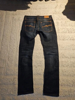 Nudie jeans - Riktigt feta Jeans från nudie i mörkblått med skön fade. Det står storlek 34:34 men är snarare W32 i midian. Mått visas längre ner. Modell: Tube Tom Färg: Gloom Blue Storlek: W34 L34 Material: 98% ekologisk bomull, 2% elastan Passform: Slim fit Mått (cm): • Midja: 42-43 • Innerben: 85-86 • Ytterlänad: 111 Benöppning: 18 Pris är ej hugget i sten