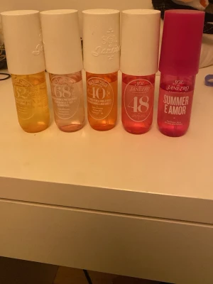 Sol de Janeiro parfym mist set - Fem olika Sol de Janeiro parfym mist i färgglada flaskor: gul, ljusrosa, orange, röd och cerise. Flaskorna har rundad form och vita eller rosa lock. Doftnamn och nummer syns på framsidan. Perfekt för dig som gillar fräscha och söta dofter. Alla kostade runt 270-300 styck