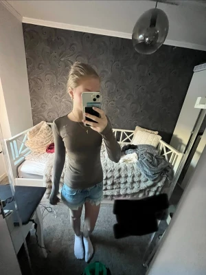 Brun långärmad tröja  - Snygg brun långärmad topp med rund halsringning från Gina! Modellen är slim fit och passar perfekt till jeans eller shorts. Den är lite trasig vid sömnen där nere.