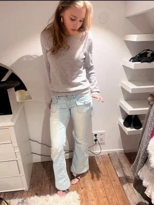 Stickad tröja från Vila - En stilren ljusgrå tröja med rund hals och långa ärmar. Tröjan har en enkel och klassisk design med ribbade muddar vid ärmslut och nederkant. Perfekt att matcha med jeans eller kjol för en avslappnad look. Nopprig. 