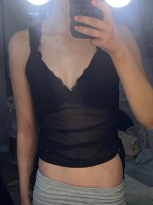 Svart linne - Säljer en svart linnetopp från H&M med spetsdetaljer längs urringningen och breda axelband. Toppen är figurnära och har en lätt look som ger en trendig vibe. Perfekt att styla med jeans eller kjol för en cool outfit. Säljer den för den inte kommer till användning och skriv om du har frågor 💕