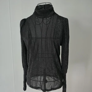 Blus - En superfin och feminin blus som passar lika bra till vardag som till fest ✨ Tyget är tunt och lätt med en fin glittrig effekt som skimrar vackert när man har den på. Den är något transparent vilket ger en elegant och trendig look (perfekt med topp under om man vill). Ärmarna är verkligen något extra – väldigt fina, speciella och ger blusen en unik touch som gör att den sticker ut 😍 Bekväm och luftig att bära. Säljes då den inte används.
