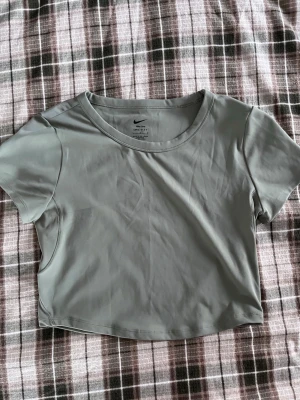 Träningstopp från Nike - Jättefin Träningstopp från Nike med logga i nacken!Grå/grön färg.                                       Säljer även byxorna