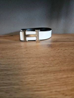 Vändbart svart och vitt läderbälte - Snyggt vändbart bälte i svart och vitt. Bältet är tillverkat i slätt skinn och passar perfekt för att lyfta vilken outfit som helst. Enkel att matcha tack vare de klassiska färgerna och den stilrena designen.