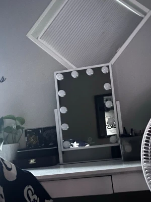 Sminkspegel med LED-belysning - Snygg sminkspegel i rektangulär form med vit ram och integrerad LED-belysning runt spegeln. Spegeln står på en stadig fot och har touch-knapp för att justera ljuset. Perfekt för sminkning och styling, ger bra ljus och modern känsla till rummet.