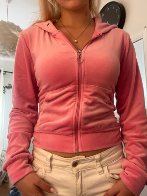 Rosa velour hoodie med dragkedja - Säljer en rosa hoodie i mjuk velour med dragkedja framtill och huva. Hoodien har en croppad passform och fickor på sidorna. Perfekt för en chill och trendig look.