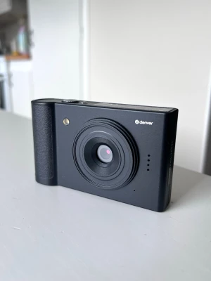 Denver digitalkamera Full HD & 8x zoom - Smidig digitalkamera från Denver, perfekt för vardagsbilder och videor - klassiska digicam-looken med blixtbilder och nostalgiska semesterbilder.   • Utrustad med 5 MP CMOS-sensor (upp till 48 MP interpolerat).  • Inspelning i Full HD 1080p.  • 8x digital zoom.  • 2,8-tums skärm.  • Inget linsskydd.   Laddas via USB-C och använder microSD-kort (medföljer ej). Perfekt som första kamera eller som en smidig extrakamera att ha med på resan. Testad en gång. Skick och tillbehör enligt bilderna. 