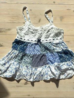 Babydoll topp med mönster - Topp med både spetsliknande tyg, rosett och massa fina olika mönster. Super gullig kjol topp! Justerbara band. Ingen lapp finns kvar. Passar nog xxs - s (om du tittar på ryggen så är den delen strechtig det andra inte). Inga defekter men jag har användt den en del!