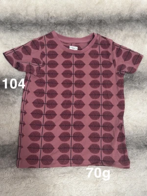  t-shirt med bersåmotiv - Säljer en t-shirt med mörkare bersåmönster över hela tröjan. T-shirten har korta ärmar och rund halsringning. Perfekt för dig som gillar unika mönster och en avslappnad stil.🌸 Fint använt skick. Storlek 104
