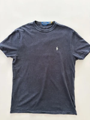 Mörkblå t-shirt från Polo Ralph Lauren - Klassisk mörkblå t-shirt från Polo Ralph Lauren med rund halsringning och korta ärmar. Storlek S men är stor i storleken sitter som en M! Hör av dig vid minsta fundering😊