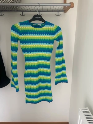 Randig kortklänning från Bershka - Klänning från Bershka. Klänningen har långärmad design och öppen rygg. Strandklänning. Använd fåtal gånger. Tyget har sprättats något på ett ställe (se bild).