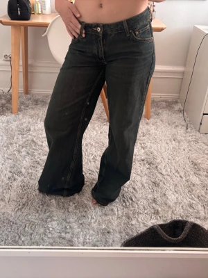 Mörkblåa vida jeans med låg midja - Säljer ett par mörkblåa jeans med låg midja och vida ben. Jeansen har klassisk femficksdesign och kontrastsömmar. Perfekta för en avslappnad och trendig look. Materialet känns som bomullsdenim.