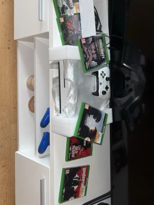 1TB Xbox One S med spel utan handkontroll   - Säljer en vit Xbox One S med tillhörande vit handkontroll och flera populära spel, bland annat Call of Duty och Red Dead Redemption 2. Konsolen har en stilren design i plast och passar perfekt för gamingkvällar.