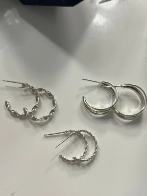 3pack silvriga hoops örhängen - Säljer tre par stilrena hoops i silverfärgad metall. Ett par har tvinnad design, ett par är släta och ett par har en mer markerad twist. Pluppar medföljer om det önskas:)