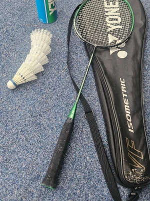 Badmintonracket med fodral och fjäderbollar - Säljer ett badmintonracket från Yonex med svart fodral och flera vita plastfjäderbollar. Racket har svart och grönt handtag och fodralet har axelrem. Perfekt för dig som vill spela badminton med kompisar.