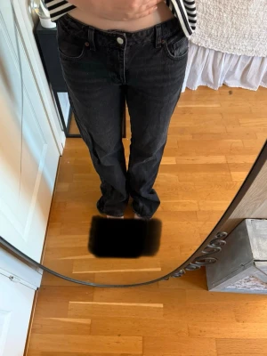 Svarta raka jeans med normal passform - Säljer ett par svarta jeans med rak passform och klassisk femficksdesign. Jeansen har normalhög midja och är tillverkade i bomull. Perfekta för dig som gillar en enkel och stilren look.