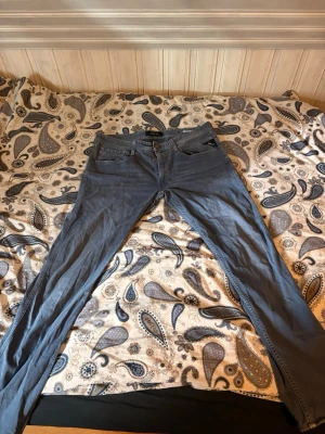 Blå jeans från Replay - Säljer ett par klassiska blå jeans från Replay med normal passform. Jeansen har fem fickor, dragkedja och knapp i midjan. Perfekta till vardagslooken och lätta att matcha med olika stilar.