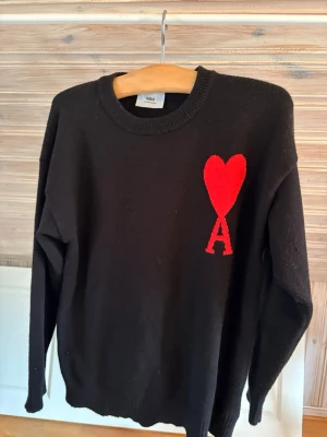 Svart stickad tröja från Ami - Snygg svart stickad tröja från Ami. Tröjan har långa ärmar och ribbade muddar vid hals, ärmslut och nederkant. Perfekt för dig som gillar stilrena detaljer.