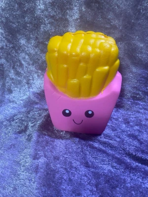 Squishy pommes frites leksak - Rolig squishy leksak formad som pommes frites i en rosa förpackning med ett gulligt ansikte. Perfekt att klämma på när du vill stressa ner eller bara ha något sött på skrivbordet. Tillverkad i mjukt skumgummimaterial.