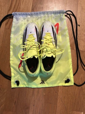 Adidas F50 elite gul/vita  - Säljer ett par riktigt snygga fotbollsskor från Adidas i vitt och neongult med svarta detaljer och röda inslag. Skorna är använd en gång och det syns knappast att dom är använd annars är dom helt nya och perfekta. Säljer dom på grund  ut av att dom inte passar mig.