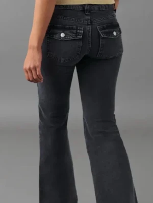 Svarta bootcut jeans med fickdetaljer - Snygga svarta bootcut jeans med fickor bak som har lock och knappar. Jeansen har en klassisk femficksmodell framtill och är tillverkade i denim med lätt tvättad look. Perfekta för dig som gillar en retroinspirerad stil.