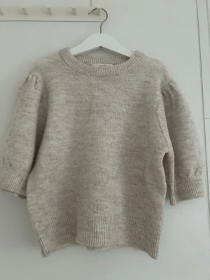 Beige stickad tröja med puffärm - Mysig beige stickad tröja med puffärmar från Gina tricot i storlek 146/152.