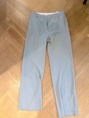 Mintgrön kostymbyxor från Filippa K - Snygga mintgröna / ljusblå kostymbyxor från Filippa K i storlek 36. Byxorna har hällor för skärp och diskret dragkedja fram. Tillverkade i ett tunt, mjukt tyg som ger en clean look🤍