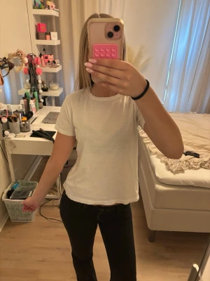 Vit basic t-shirt i bomull - En enkel vit t-shirt med rund hals och korta ärmar. Tillverkad i mjuk bomull och har en normal passform som funkar till allt. Perfekt basplagg för garderoben.