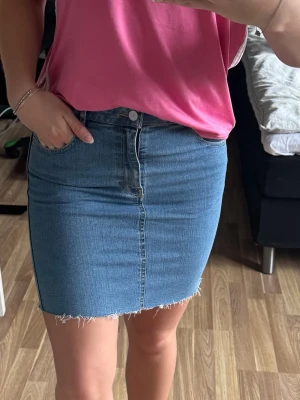 Snygg blå jeanskjol - Blå jeanskjol med fickor och fina detaljer. Storlek 38, knappt använd.