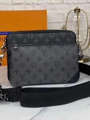 Svart axelväska med monogram - Snygg svart axelväska från Louis Vuitton med klassiskt monogrammönster i grå toner. Väskan har justerbar axelrem, silverfärgade detaljer och en praktisk ytterficka med dragkedja. Tillverkad i tåligt lädermaterial och passar perfekt för dig som gillar stilrena accessoarer.