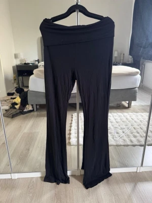 Svarta utsvängda leggings - Säljer ett par svarta leggings med utsvängda ben och bred linning i midjan. Mjukt och stretchigt material som sitter skönt på kroppen. Perfekta till en avslappnad och trendig look.