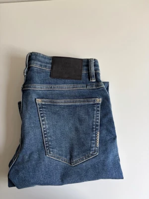 Neuw jeans - Jeans från Neuw, knappt använda. Storlek 29/32Snygga blå slim fit jeans med klassisk femficksdesign och en mörk skinnpatch i midjan. Jeansen har en lätt tvättad look med subtila slitningar och raka ben. Perfekta för en avslappnad och trendig stil. 