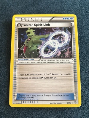 Pokémonkort Tyranitar Spirit Link - Pokémonkortet Tyranitar Spirit Link är ett tränarkort från Pokémon TCG. Kortet har gul ram, silverfärgad bakgrund och en bild på Tyranitar med två ringar. Det är ett Item-kort och fungerar som Pokémon Tool. Perfekt för samlare eller Pokémonspelare.