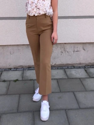 Kostymbyxor från Gina Tricot  - Snygga bruna kostymbyxor med utsvängda ben. Byxorna har klassiska pressveck och bälteshällor i midjan. Superbekväma och sitter bra men säljer pga upplever att dom är lite för korta på mig som är 171cm.  Använda någon enstaka gång men är i jättefint skick. Svårt att fånga upp färgen på bilderna pga ljuset men färgen är samma bruna färg som på första och andra bilden.