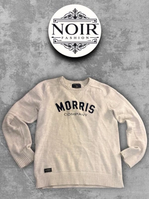 Beige stickad tröja Morris - Snygg beige stickad tröja från Morris med mörkblå text på bröstet. Tröjan har rund halsringning, långa ärmar och ribbade muddar vid ärmslut och nederkant. Perfekt för en avslappnad och stilren look.