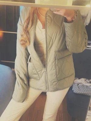 Quiltad grön vindjacka med dragkedja - Snygg quiltad vindjacka i ljusgrönt med dragkedja framtill och stora fickor med lock. Inga defekter 