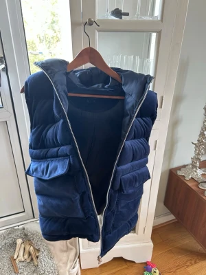 Mörkblå dunväst med huva - Skön mancester väst från Vendiera stl S, OBS de felen är att en knapp till fickorna kan öppnas ibland,