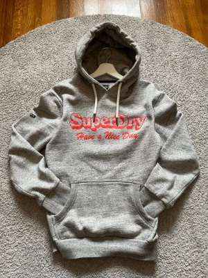 Grå Superdry Hoodie - Tjabba!! Säljer denna fina och unika Superdry Hoodien. Väldigt bra skick, knappt använd. Storlek M. Skriv gärna vid frågor eller funderingar😊