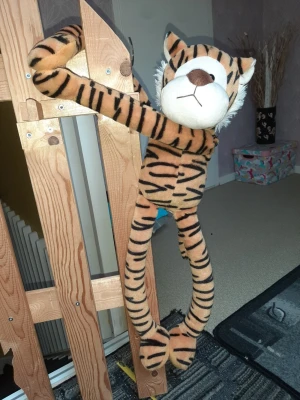 Mjukistiger med långa armar och ben - Stor gosedjurstiger i mjukt tyg med orange och svarta ränder, vit nos och öron. Den har extra långa armar och ben, perfekt att hänga eller krama. Ansiktet är broderat och materialet är plysch. Märke saknas.