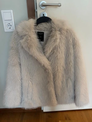 Beige fuskpälsjacka  - Säljer en fluffig beige fuskpälsjacka från Lager 157, The Black Label Collection . Jackan har en oversized passform, bred krage och stängs framtill. Perfekt för dig som vill ha en trendig och varm look under vintern. Materialet är mjukt och ger en lyxig känsla. Aldrig använd, ordinarie pris Ca 500. I storlek Xs/S💞 