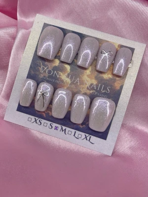 Cloud (M);Short Ballerina;Curved - Säljer ett set handgjorda press-on naglar i storlek M: 16 mm, 12 mm, 12,5 mm, 11,5 mm, 10 mm. Naglarna är ljuslila med skimrande glitter och dekorerade med små silverrosetter. Formen är kort kistformad och de har en elegant, glansig finish. Perfekt för dig som vill ha en söt och trendig look.