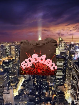 Brun SP5DER hoodie med spindelnätsgrafik - Cool brun SP5DER hoodie från Sp5der med stor röd spindelnätsgrafik och rosa 3D-tryck på bröstet. Gula prickar längs ärmarna ger extra detaljer. Hoodien har en klassisk huva och är tillverkad i mjukt bomullsmaterial. Perfekt för dig som gillar streetwear och unika prints.