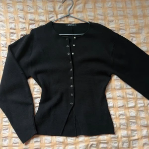 Figursydd kofta med knappar - Stilren svart kofta från Gina Tricot med en figursydd look, rund halsringning och knappar framtill. Materialet är mjukt och bekvämt🎀varan är använd max 5 gånger!!