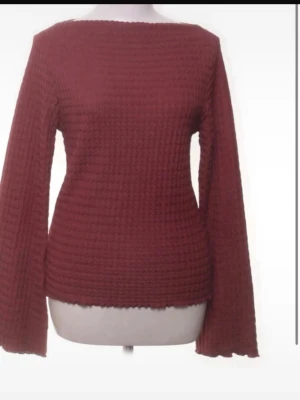 Mörkröd stickad tröja med vida ärmar - En mörkröd stickad tröja med breda, vida ärmar och en rak, något boxig passform. Tröjan har ett diskret strukturmönster och en enkel rund halsringning. Perfekt för dig som gillar en avslappnad och trendig look.